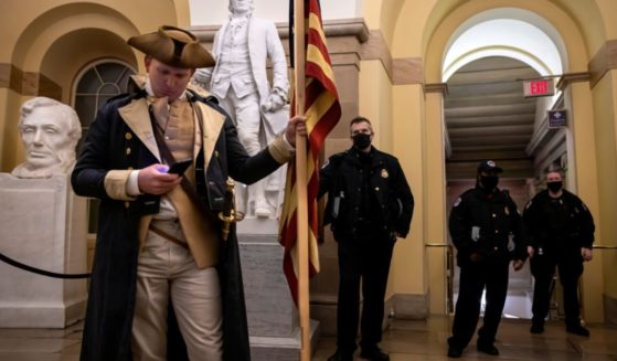 Capitol Police look on as a protester dressed as George Washington checks his phone before being pushed out of the building on Jan. 6, 2021. Supporters of then-President Donald Trump staged a mostly peaceful protest at the Capitol as Congress debated the 2020 presidential election electoral vote certification.