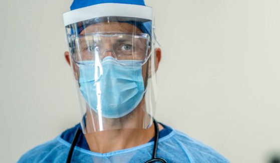 A medical professional is wearing full protective wear in a hospital setting.