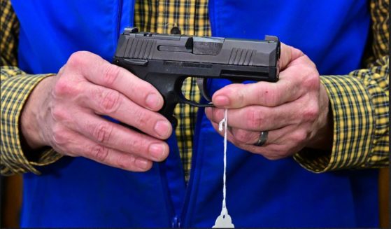 A gun shop owner displays a Sig Sauer pistol in a file photo from Feb. 24.