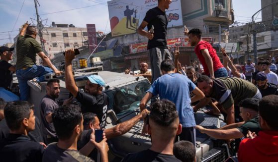 Palestinians gather around an Israeli army vehicle that Palestinian militants drove from Israel into Gaza following the Hamas terrorist attacks on Oct. 7.