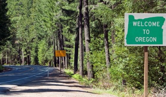 a roadside sign in the forest that says "welcome to Oregon"