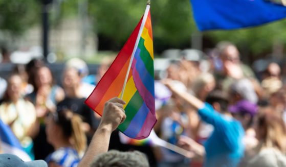 This image shows a group of people that are a part of a "Pride" parade in Montreal, Canada. One person is waving a rainbow flag.