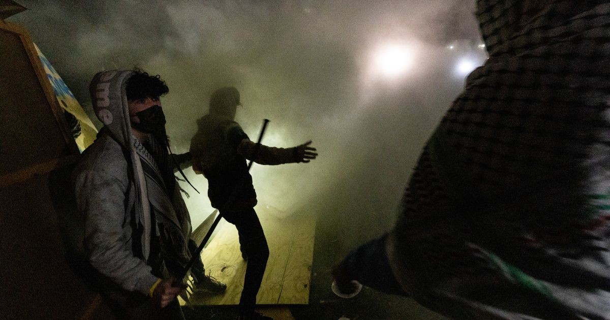 Pro-Palestinian demonstrators attempt to rebuild a barricade around their encampment while surrounded in tear gas on the campus of the University of California Los Angeles on Wednesday.
