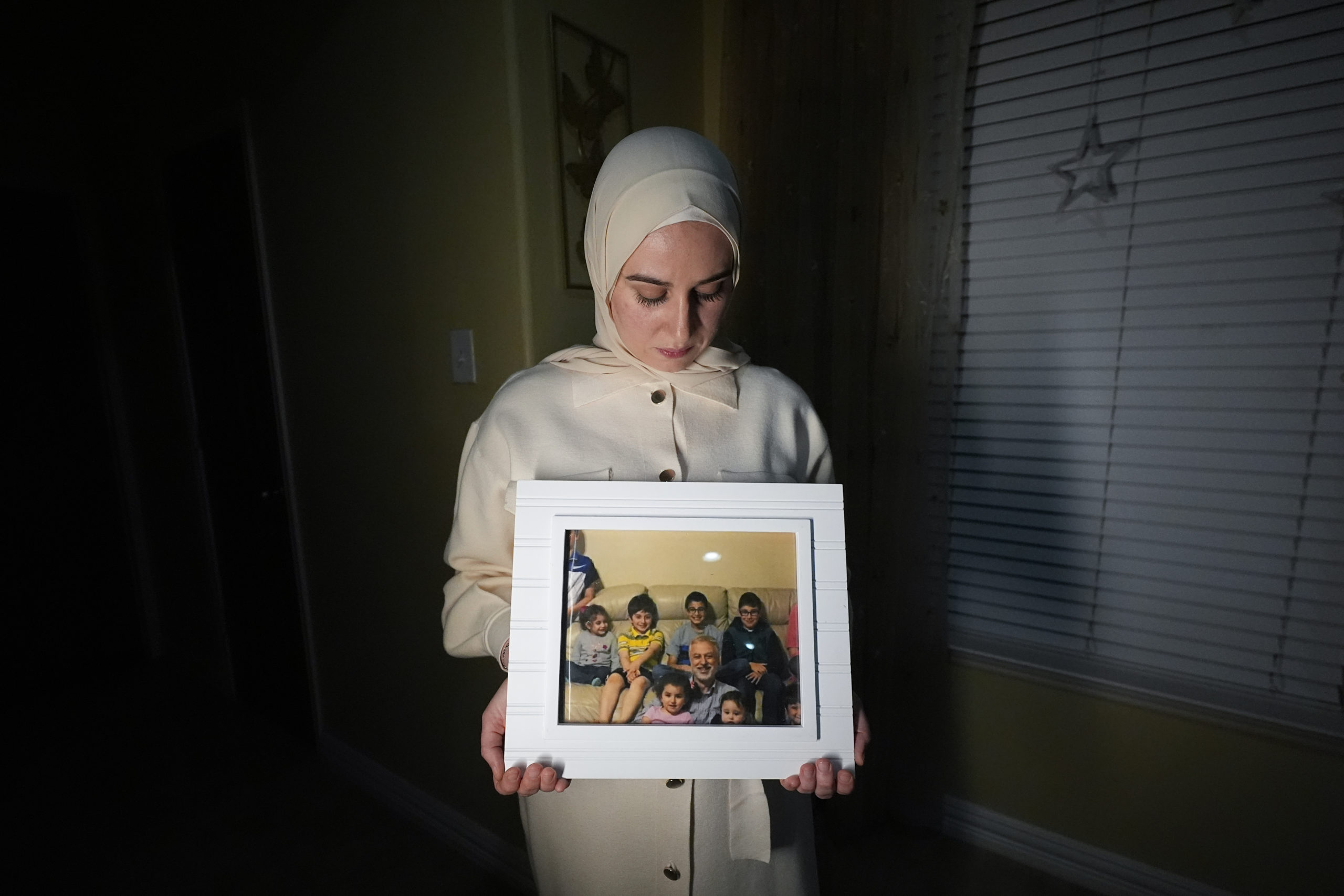 Maryam Kamalmaz hold a photo of her father with some of his 14 grandchildren in Grand Prairie, Texas, in a file photo from Jan. 17. U.S. officials have developed intelligence suggesting that Majd Kamalmaz, an American citizen who disappeared seven years ago while traveling in Syria has died,