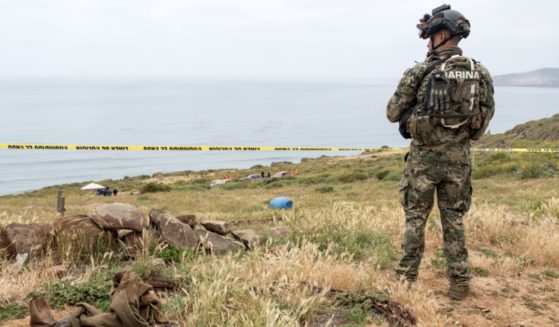 A Mexican marine stands guard near La Bocana Beach in Baja California on Friday as investigators work where the bodies believed to be a missing American and two Australian brothers were found.