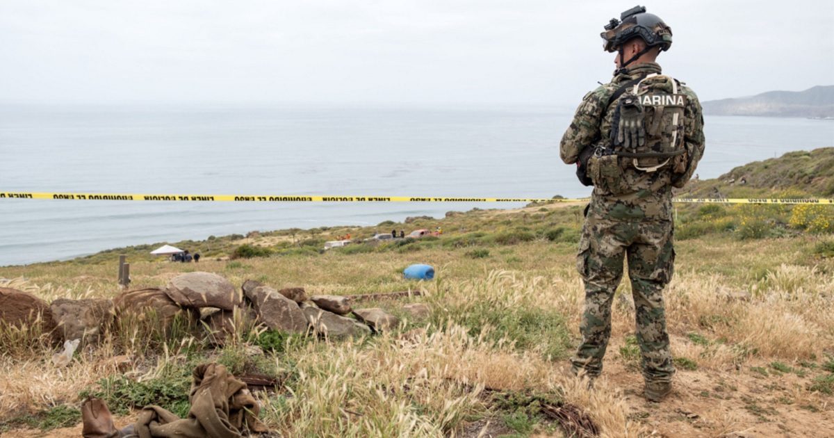 A Mexican marine stands guard near La Bocana Beach in Baja California on Friday as investigators work where the bodies believed to be a missing American and two Australian brothers were found.
