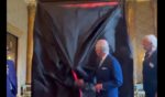 The U.K.'s King Charles III unveils a portrait of himself on Tuesday in London.