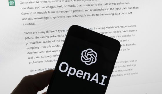 The Open AI logo is seen on a mobile phone in front of a computer screen displaying output from the company's ChatGPT software in Boston on March 21, 2023.