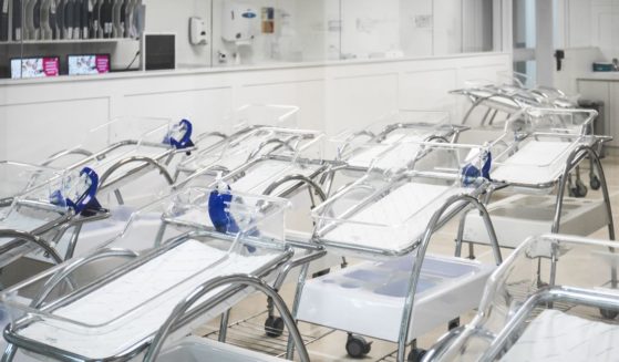 An undated stock photo shows empty cribs lined up in a hospital maternity room.
