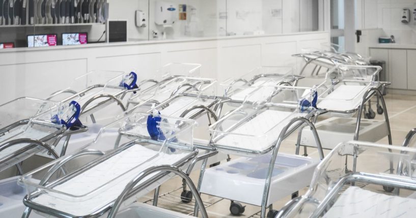 An undated stock photo shows empty cribs lined up in a hospital maternity room.