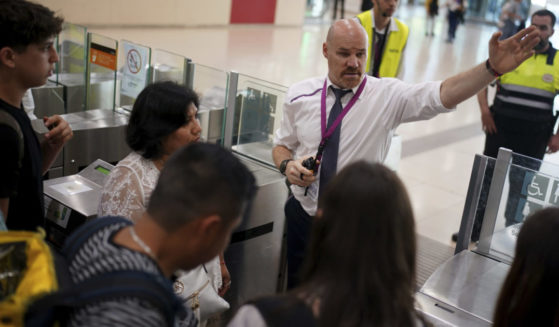 employees giving directions to passengers crowded at the entrance to the platforms at Sants train station in Barcelona