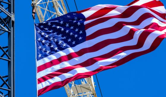 The American flag waves proudly from construction cranes under a brilliant blue sky.