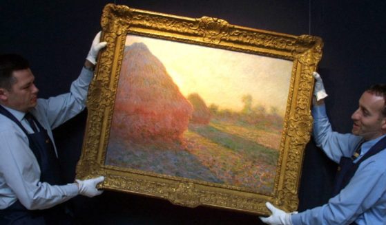 Sotheby`s staff hang the painting "Haystacks" by French artist Claude Monet in London 26 April 2001.