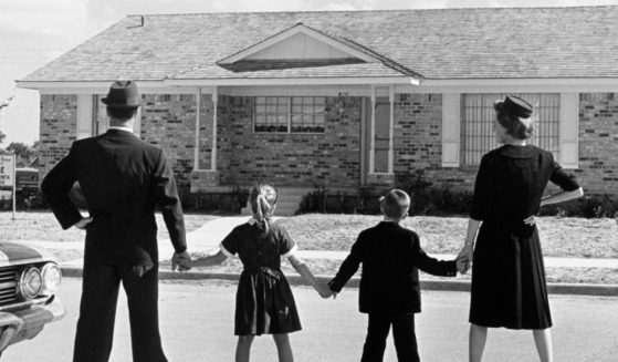This Getty stock image shows a family in 1950 standing outside of a house for sale.