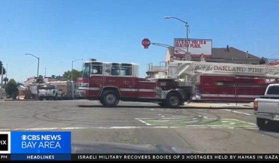 A firetruck moves through a busy Oakland intersection where traffic signals have been replaced by four-way stop signs.