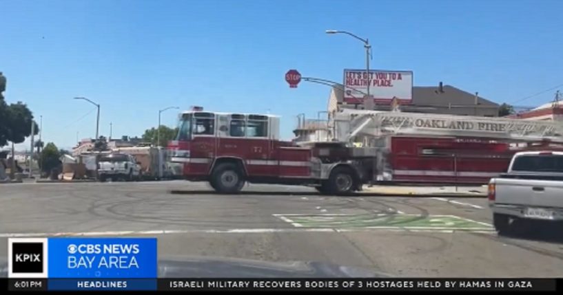 A firetruck moves through a busy Oakland intersection where traffic signals have been replaced by four-way stop signs.