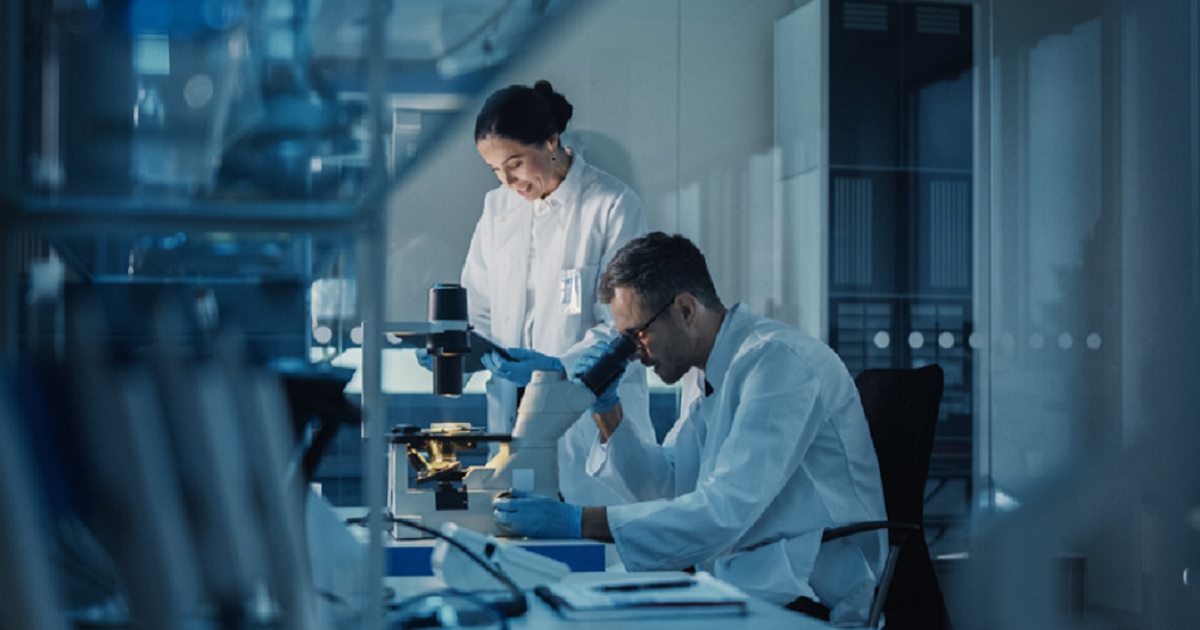 A scientist looks in a microscope in a lab.