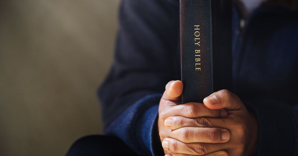 This photo shows hands holding tightly to the Holy Bible.