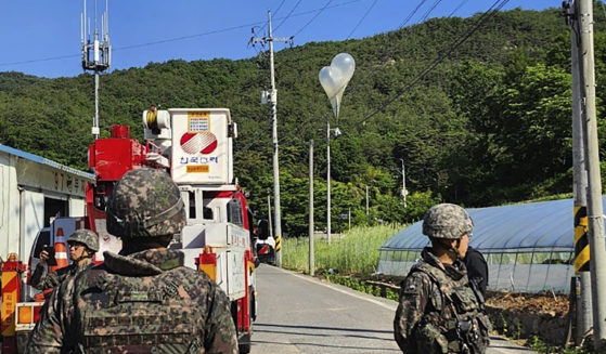 Balloons with trash, presumably sent by North Korea, hang on electric wires as South Korean army soldiers stand guard in Muju, South Korea, on Wednesday. North Korea launched more trash-carrying balloons toward the South after a similar campaign earlier in the week, according to South Korea's military, in what Pyongyang calls retaliation for activists flying anti-North Korean leaflets across the border.