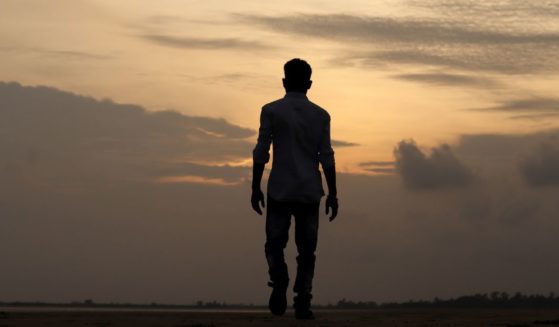 A man walks towards the sunrise.