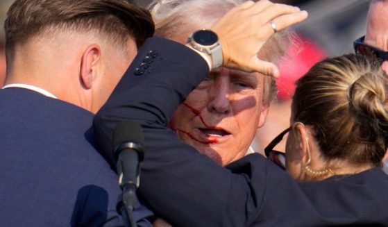 Former President Donald Trump is helped off the stage by U.S. Secret Service agents after an assassination attempt at a campaign event in Butler, Pennsylvania, on Saturday.