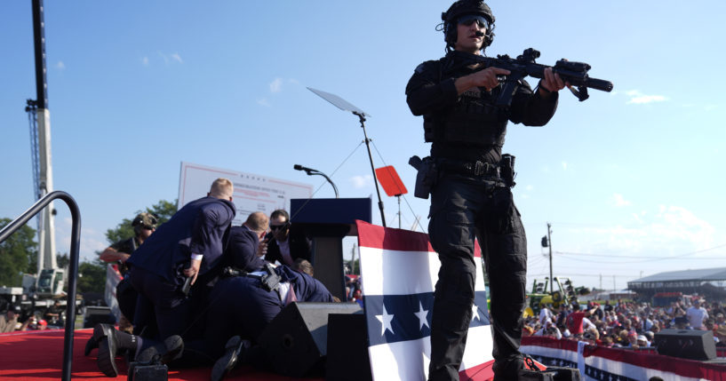 An armed law enforcement officer mans the stage durign the aftermath of the assassination attempt on former President Donald Trump on July 13 in Butler, Pennsylvania.