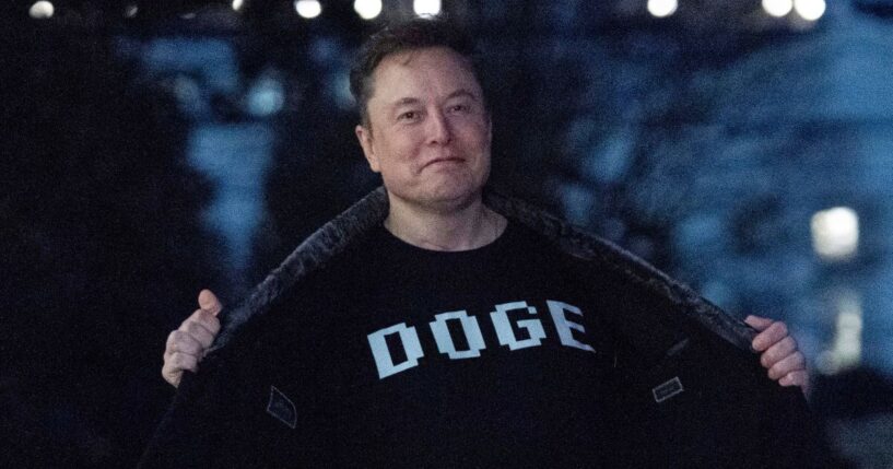 Elon Musk flashes his T-shirt that reads "DOGE" to the media as he walks on the South Lawn of the White House, in Washington, March 9, 2025.