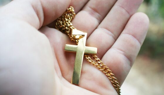 A gold cross in the palm of a hand.