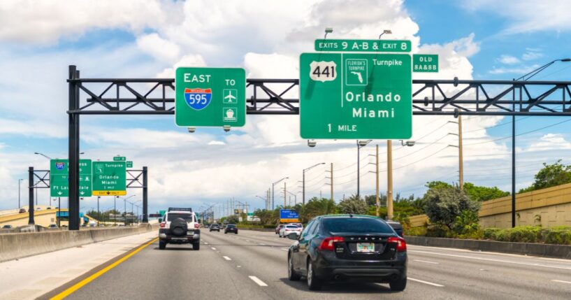 Highway traffic by Interstate 595 with an exit sign to the Florida Turnpike to Orlando in Miami-Dade County.