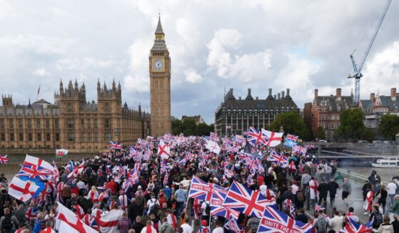 Protesters wave Union Jack and St. George's England flags during the "Unite The Kingdom" rally on Westminster Bridge by the Houses of Parliament on Sept. 13, 2025, in London, England.