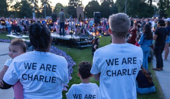 People wear t-shirts reading "WW Are Charlie" as they pay their respects during a candlelight vigil for conservative activist Charlie Kirk at a makeshift memorial at Memorial Park in Provo, Utah, on Sept. 12, 2025, after he was shot during a public event at Utah Valley University.