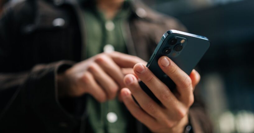 A man uses his smart phone on a city street.