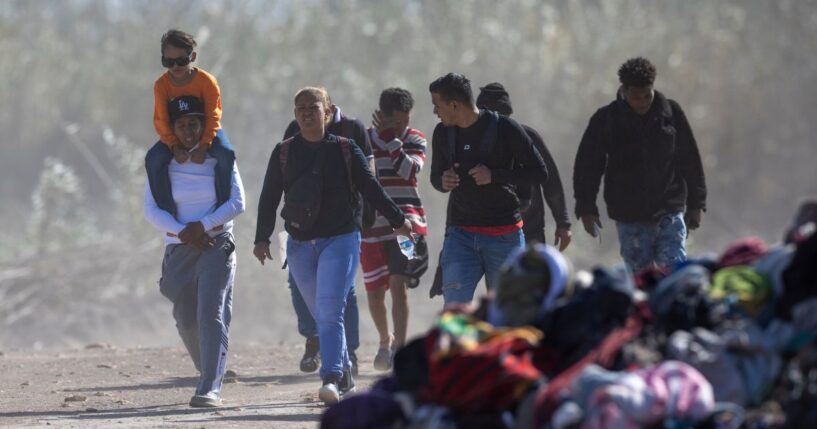 Illegal immigrants from Venezuela walk past a pile of discarded migrant clothing after crossing the Rio Grande into the United States in Eagle Pass, Texas, on Jan. 8, 2024.