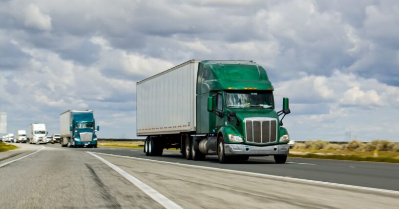 A green truck driving on Interstate 5 in California.