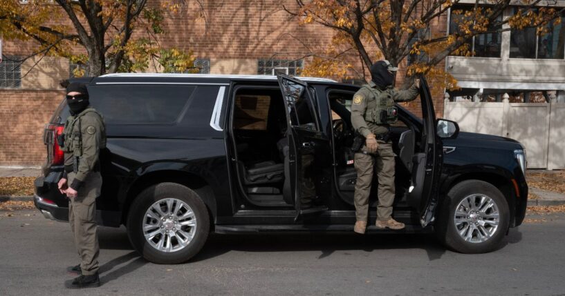 Federal agents stand guard as they are confronted by residents after making a stop while driving in a caravan through the Brighton Park neighborhood on Nov. 6, 2025, in Chicago, Illinois.
