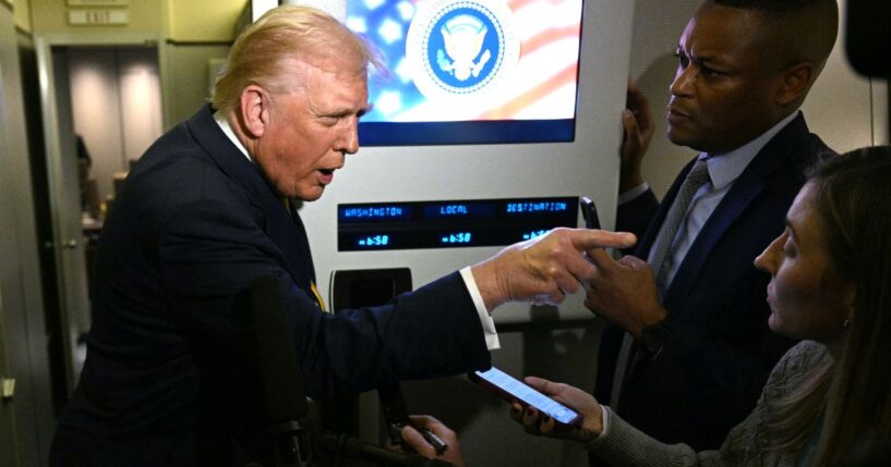 President Donald Trump points as he speaks to reporters Friday aboard Air Force One en route to Palm Beach, Florida.