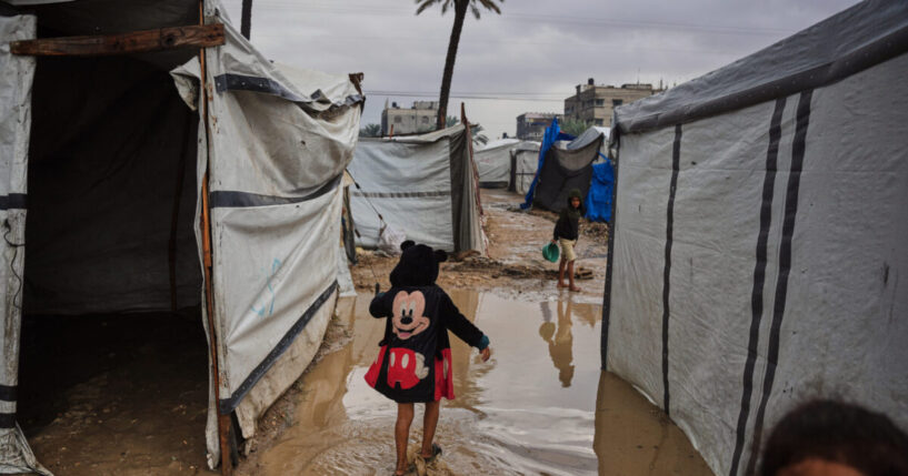 Palestinians walk through a flooded temporary tent camp Tuesday after heavy rainfall in Deir al-Balah, central Gaza Strip.
