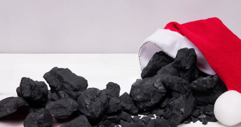 A pile of coal emerges from a Santa Claus hat.