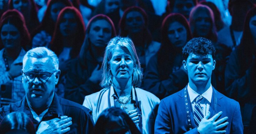 Attendees stand for the National Anthem during Turning Point's annual AmericaFest conference in Phoenix, Arizona, on Dec. 21, 2025.
