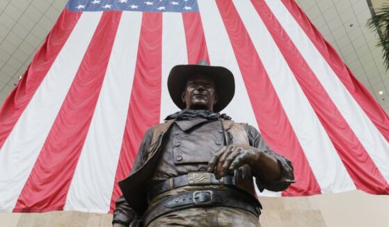 A statue of John Wayne is on display beneath an American flag in John Wayne Airport, located in Orange County, on June 28, 2020, in Santa Ana, California.