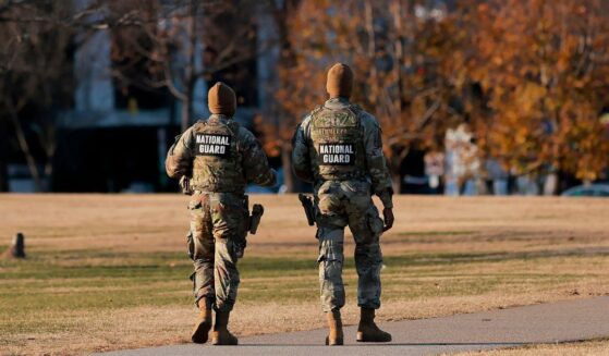 Two National Guard soldiers walk around the Washington Monument in Washington, DC on Dec. 1, 2025.