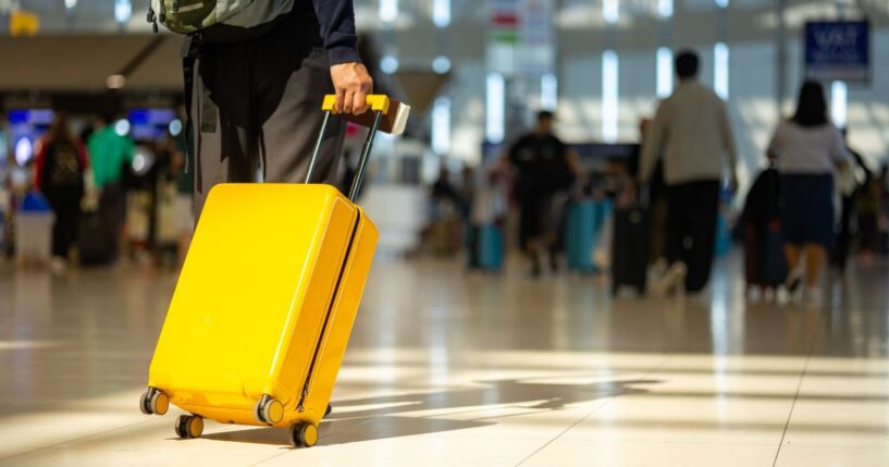 A traveler pulls his suitcase behind him at an airport.
