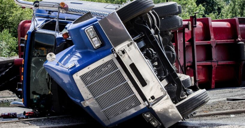 A rolled over semi-truck sits in the road.