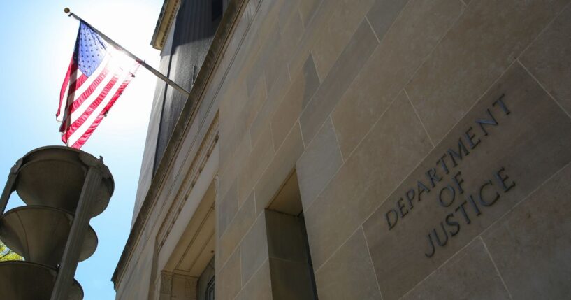 The US Department of Justice building and the American flag stand in the sun in Washington, DC.