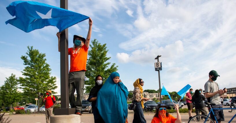 People hold up Somali flags during a protest calling for justice for Isak Aden on July 1, 2020 in Eagan, Minnesota. Isak Aden was killed on July 2, 2019 after a standoff with Eagan Police. No charges were brought against the officers involved in his death.