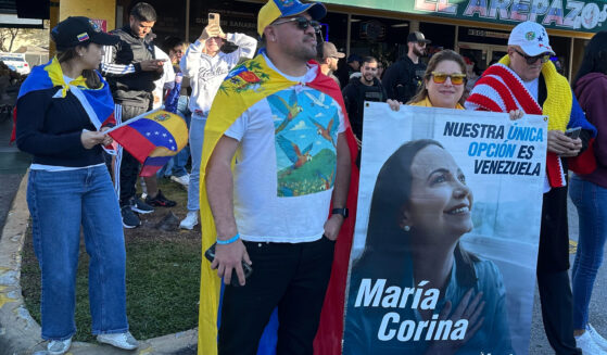 David Nuñez, Lisbeth Garcia, and Victor Gimenez gather outside El Arepazo restaurant with a banner of opposition leader and Nobel Peace Prize winner Maria Corina Machado amid celebrations following news of Venezuelan President Nicolás Maduro's capture in Doral, Florida, on Jan. 3, 2026.