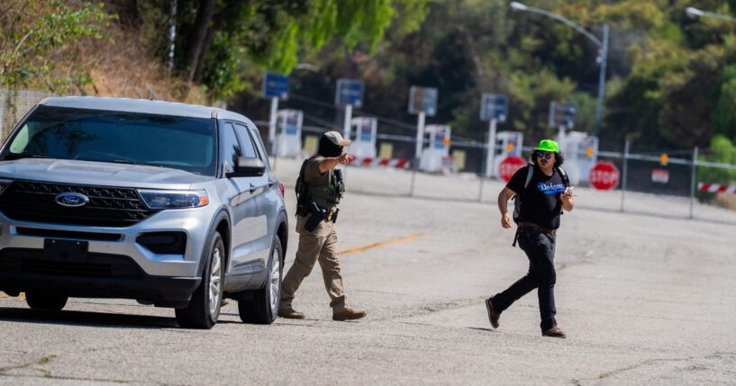A federal agent gestures toward a National Lawyers Guild legal observer attempting to record license plates near Gate E of Dodger Stadium during a brief confrontation on June 19, 2025, in Los Angeles, California.