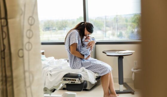A Chinese mother lovingly holds her newborn baby in a hospital room.