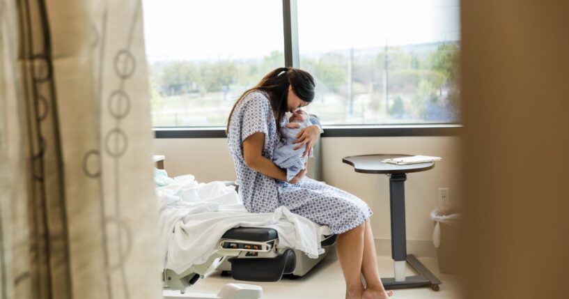 A Chinese mother lovingly holds her newborn baby in a hospital room.