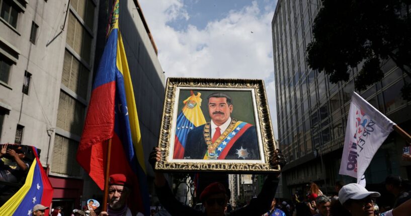 A man holds a portrait of Nicolas Maduro during a march in his support and his wife Cilia Flores after their capture by U.S. forces, on Jan. 6, 2026, in Caracas, Venezuela.